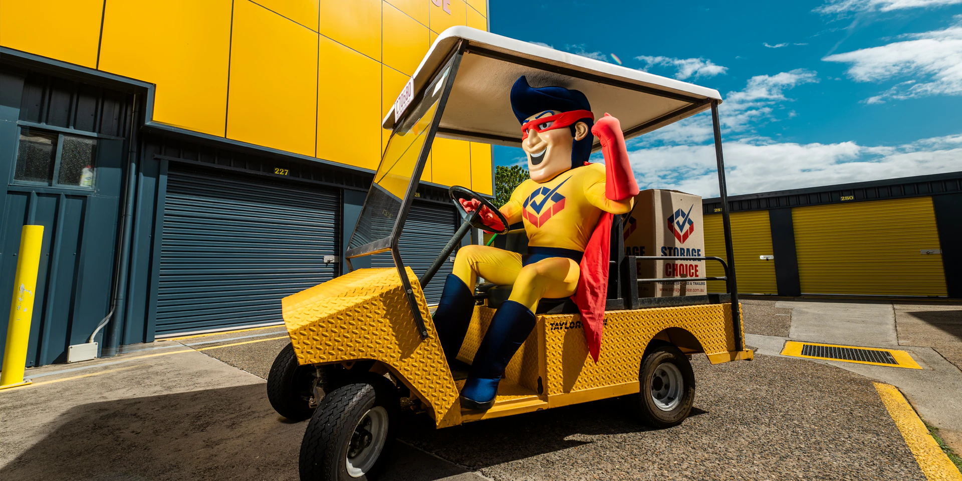 Storage Choice StoreMan mascot driving a yellow buggy with a Best Price Guarantee banner