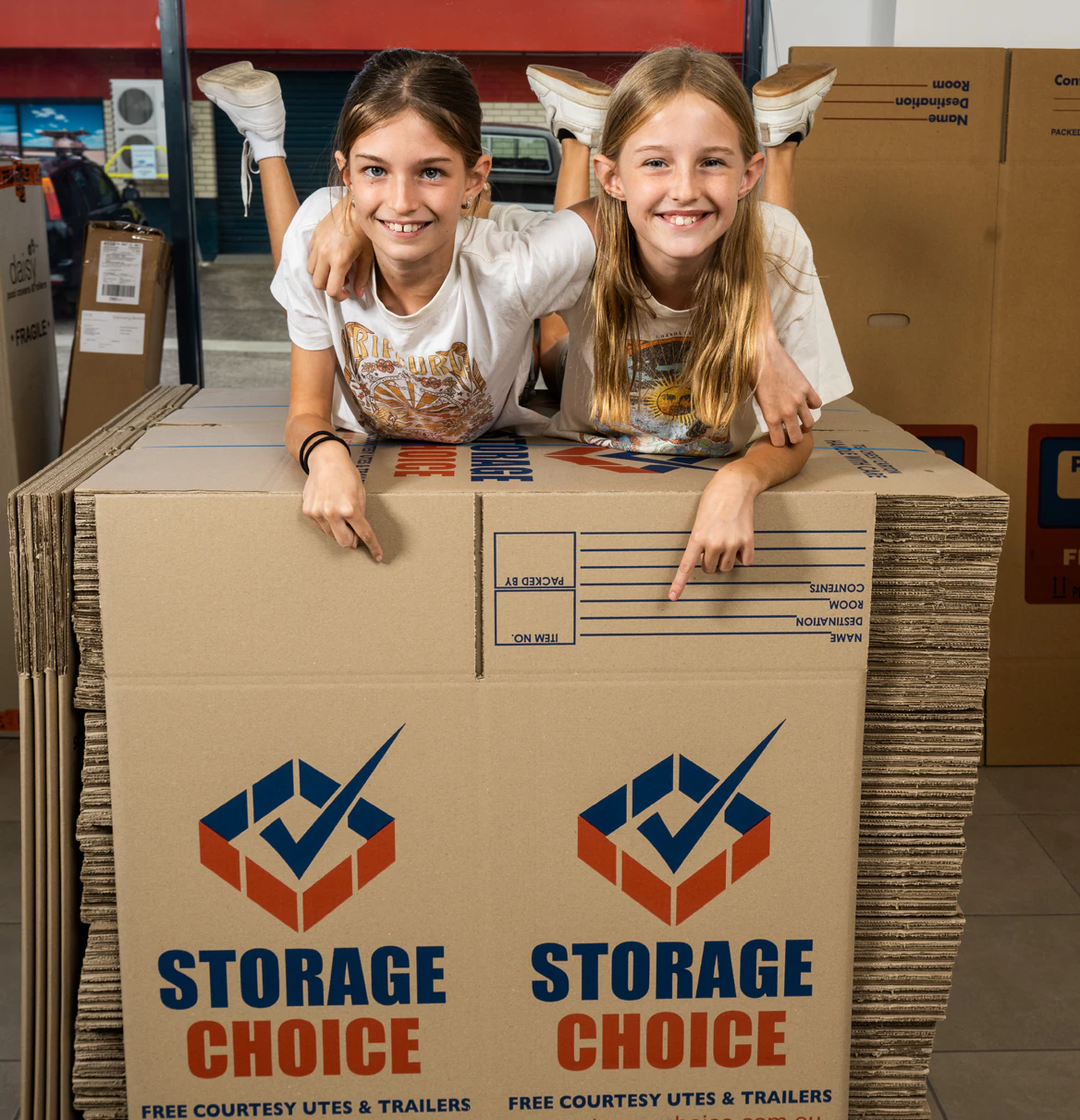Two young customers leaning on a tall stack of Storage Choice moving boxes