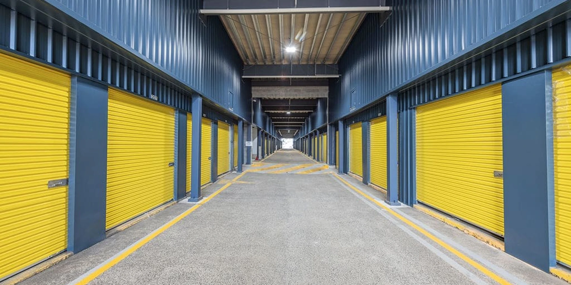 Interior corridor at a Storage Choice facility lined with yellow roller-door storage units