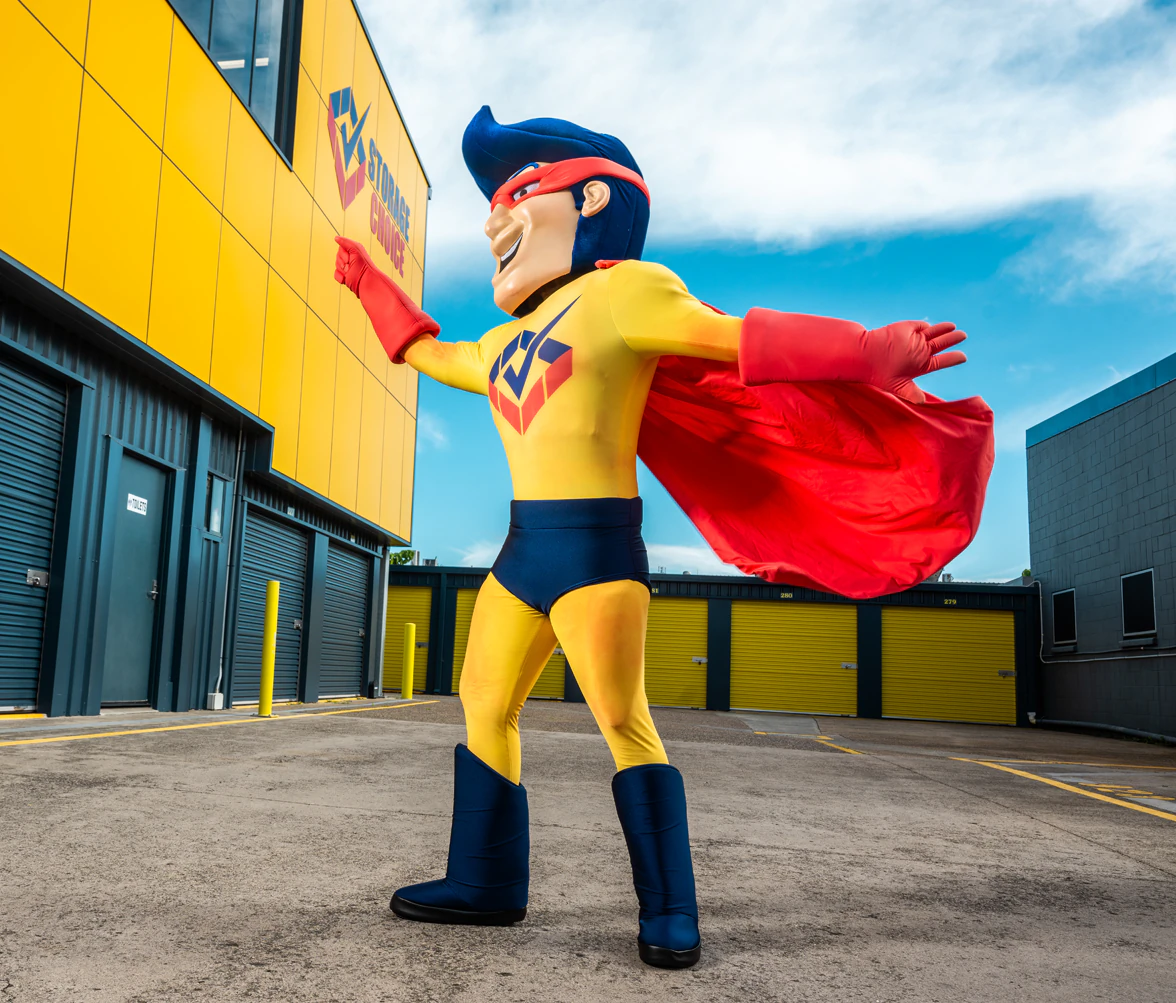 Storage Choice StoreMan mascot standing in front of a self-storage facility
