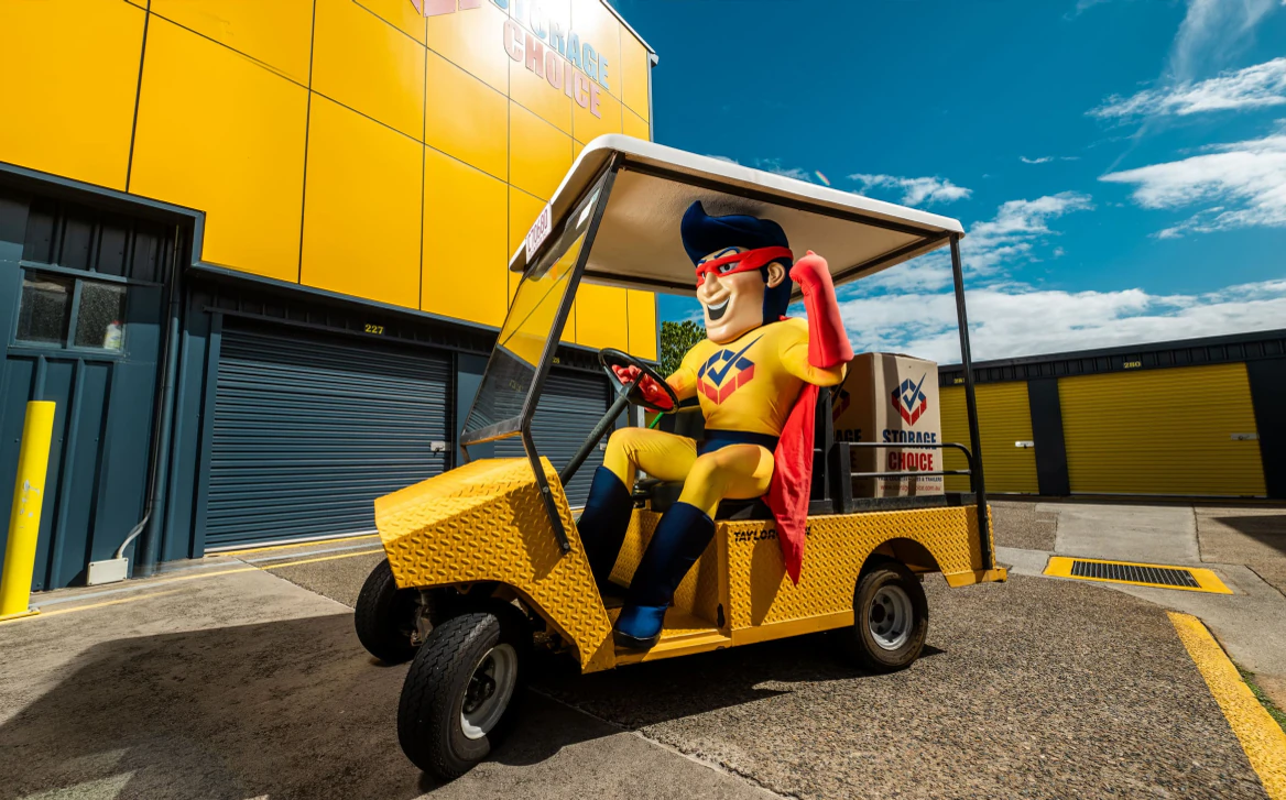 Storage Choice StoreMan mascot driving a yellow forklift buggy between storage units